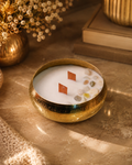 Fragnam Swarna Aura Candle with golden decorative design and elegant glass holder, showcasing a warm, inviting glow.